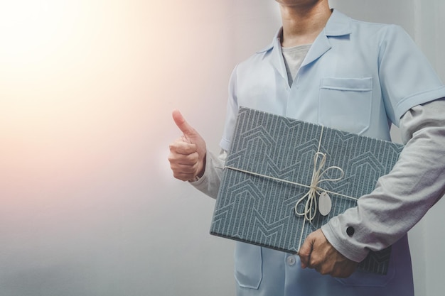 회색 배경에 고립 된 선물 상자를 들고 의사