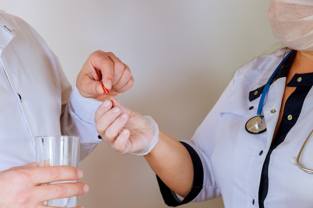 Doctor holding in gives the patient a red pill on white background