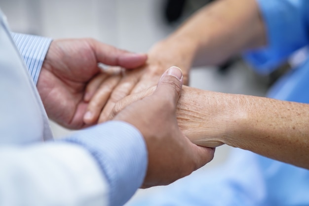 Doctor holding hands senior woman patient with love.