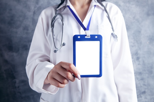 Doctor holding an identification card on a gray background