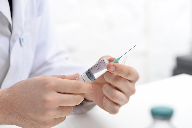 A doctor holding an injection syringe in his hand on white office