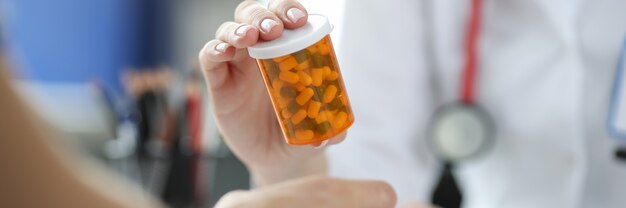 Doctor holding jar of medicines in front of patient closeup