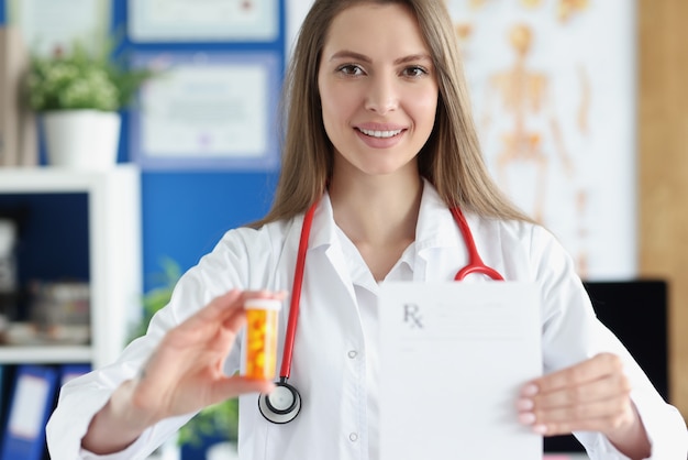 Doctor holding jar of medicines and prescription blank in clinic