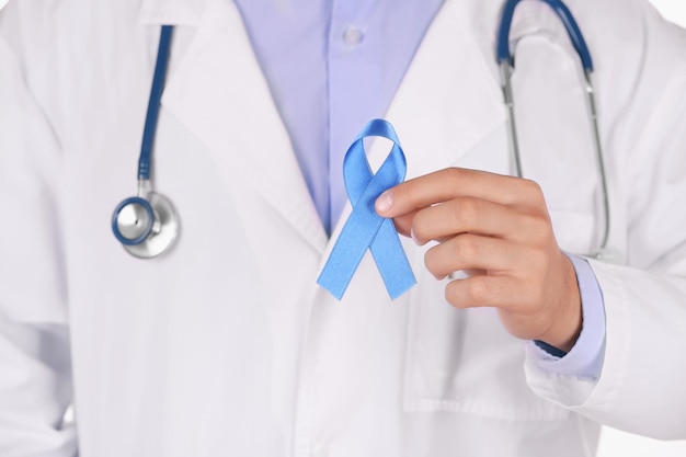 doctor holding light blue ribbon close up view prostate cancer concept