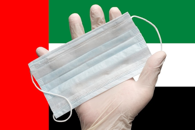 Medico che tiene in mano una maschera medica in guanto bianco su colori di sfondo bandiera nazionale dell'united... Foto Premium