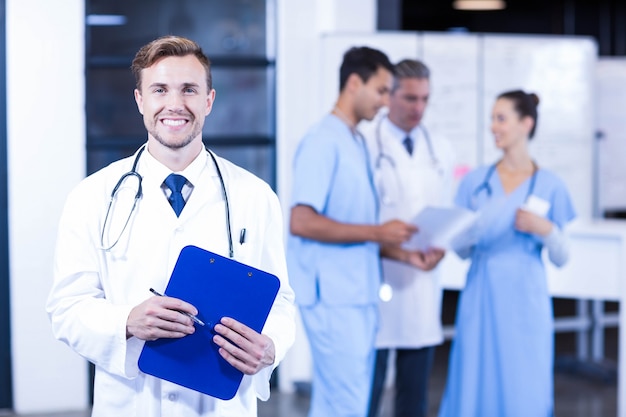 Doctor holding medical report and smiling  while his colleagues discussing