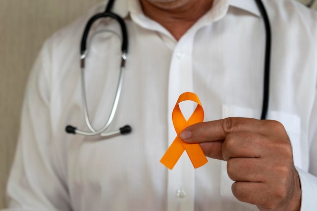 Photo doctor holding orange ribbon. campaign to prevent skin cancer, melanoma, december orange