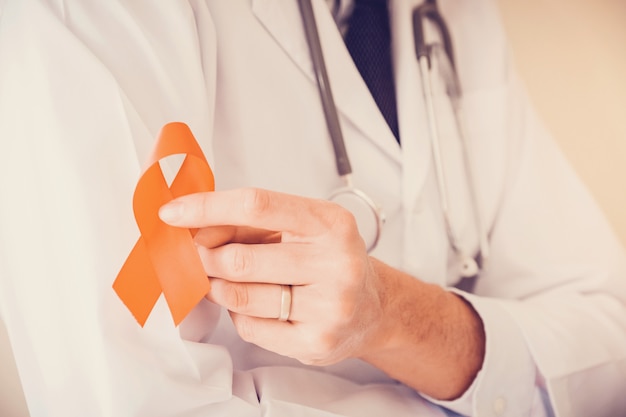 Photo doctor holding orange ribbon, leukemia cancer awareness and multiple sclerosis awareness