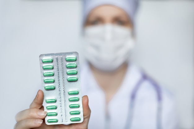 Doctor holding a pack of green pills close-up.