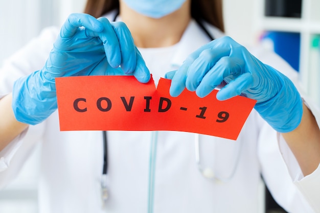 Foto medico in possesso di una scheda di carta con il testo covid-19.