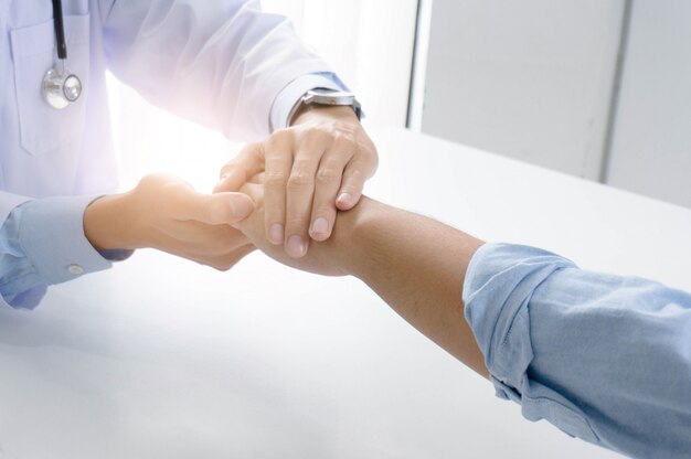 Photo doctor holding patient's hand, and reassuring his male patient helping hand concept.
