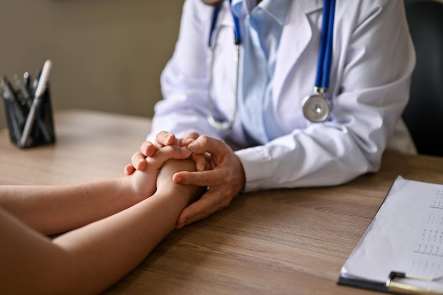 A doctor holding a patient's hands to comfort and reassure her during the medical consultation