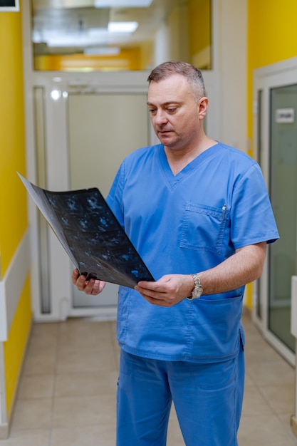 Medico in possesso di un'immagine di un flusso di lavoro di risonanza magnetica cerebrale in ospedale diagnostico. sanità, roentgen, persone e concetto di medicina.