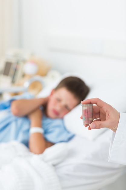 Doctor holding pill bottle with boy in ward