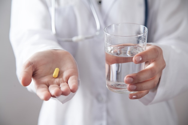 Doctor holding pill and a glass of water.