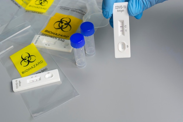 바이러스성 소설 코로나바이러스 바이러스에 대한 실험실 카드 키트의 배경이 흐릿한 COVID-19 질병에 대한 양성 테스트 키트를 들고 있는 의사