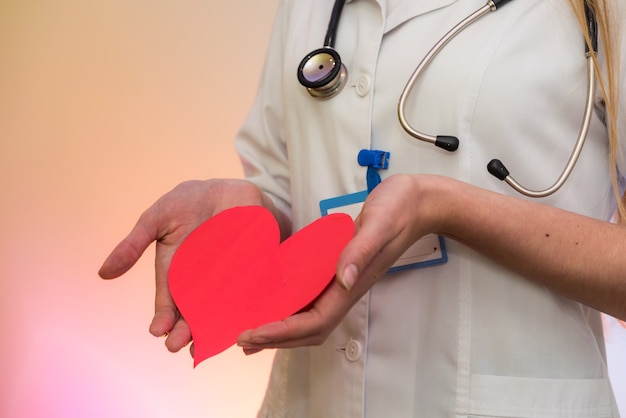 Doctor holding red heart. Cardiologist with heart shape in hands close up