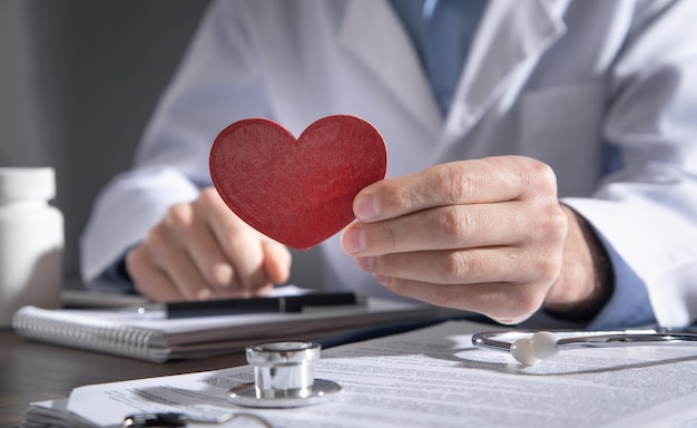 Doctor holding red heart at clinic.