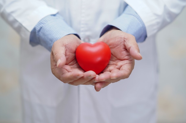 Doctor holding red heart in his hand in nursing hospital.