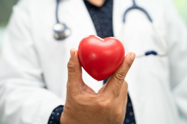 Doctor holding a red heart in hospital ward healthy strong medical concept