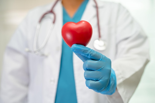 Medico che tiene un cuore rosso nel reparto ospedaliero sano forte concetto medico