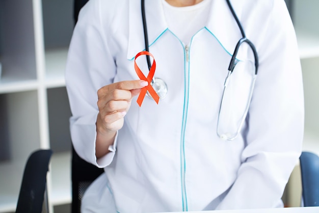 Doctor holding a red ribbon as a symbol of AIDS.