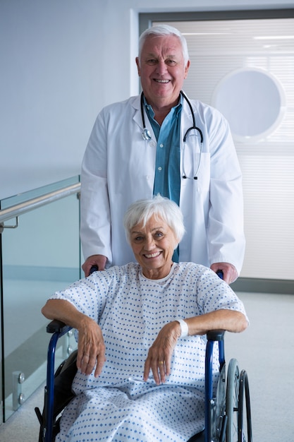 Доктор держит старшего пациента на инвалидной коляске в коридоре в больнице