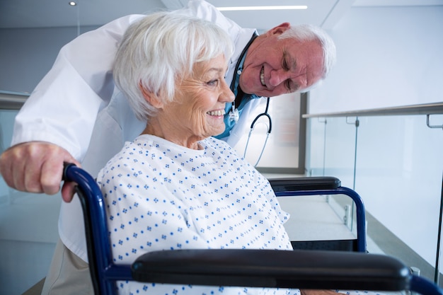 Doctor holding senior patient on wheelchair in passageway