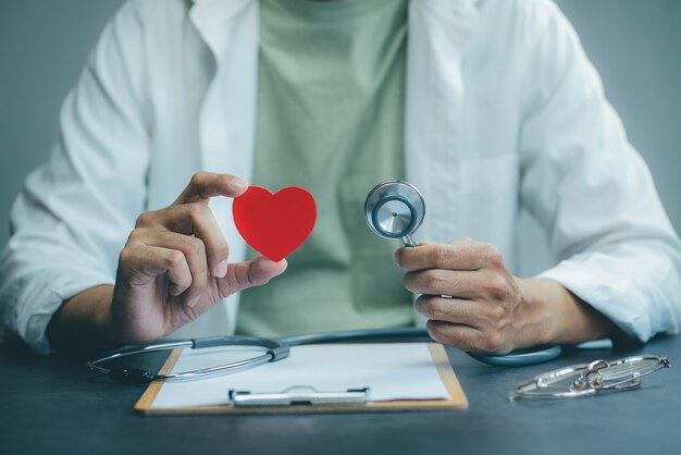 Foto medico che tiene uno stetoscopio e un cuore e lavora in ospedale