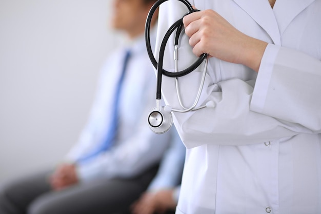 Doctor holding a stethoscope in his hands the patient on the background