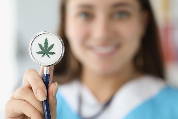 Doctor holding stethoscope with drawn marijuana leaf closeup