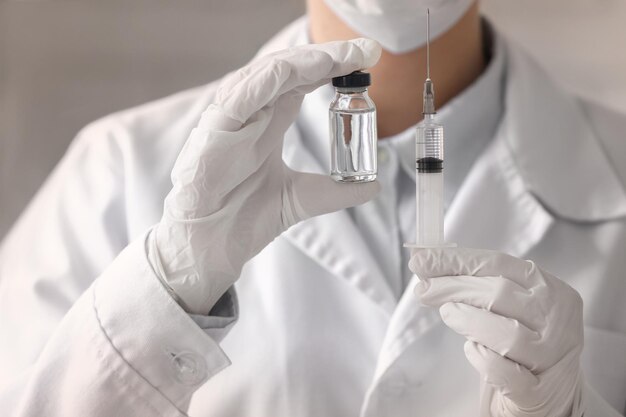 Doctor holding syringe and medicine for vaccination closeup