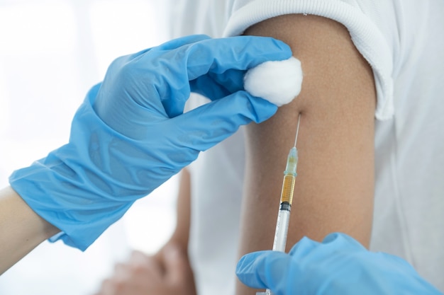 The doctor holding a syringe and was about to vaccinate a patient in the clinic to prevent the spread of the virus.