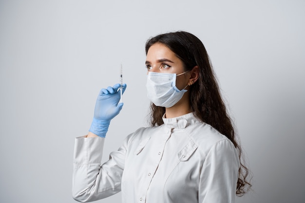 Doctor holding syringe with coronavirus vaccine. Attractive girl in medical gloves with syringe and medication