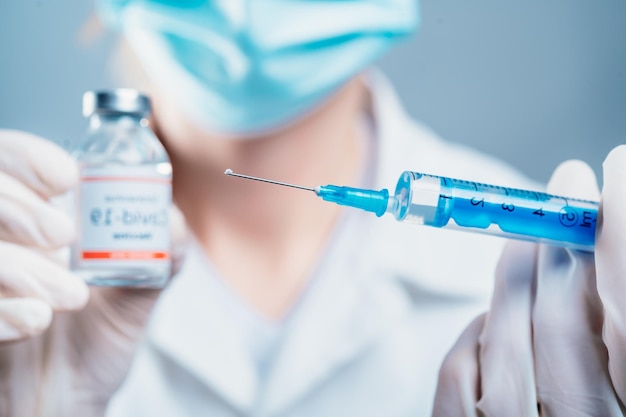 Doctor holding a syringe with a single bottle vial of Covid19 vaccine for children or adults Concept fight against virus Close up detail Medical concept vaccination hypodermic injection treatment