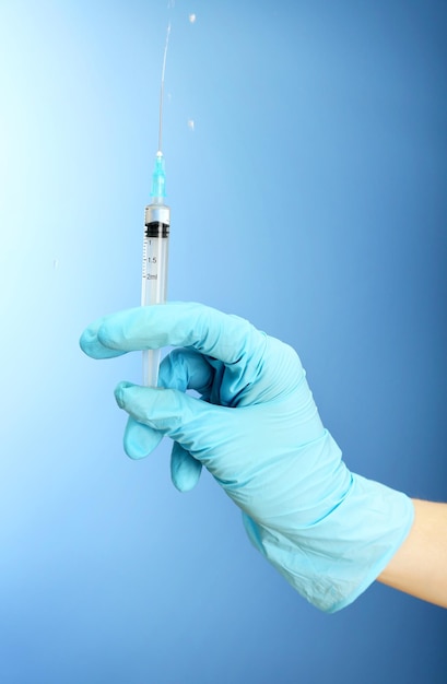 Doctor holding syringe with a vaccine on blue background