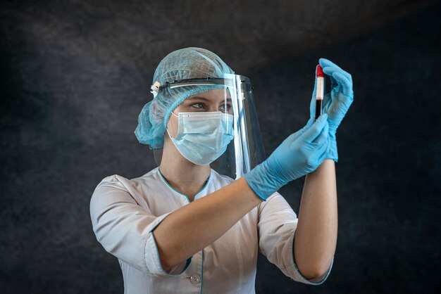 Doctor holding test tube bottle with blood sample isolated on dark background