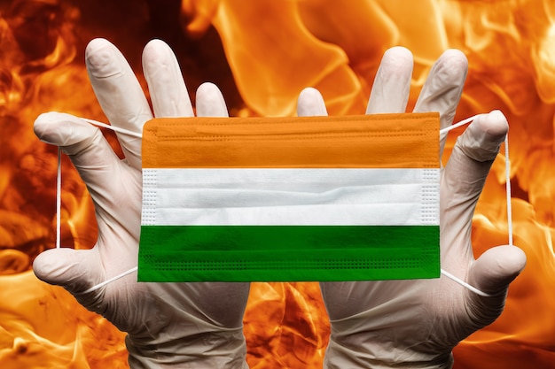 Photo doctor holding in white gloves protection medical face mask respiratory bandage with india flag