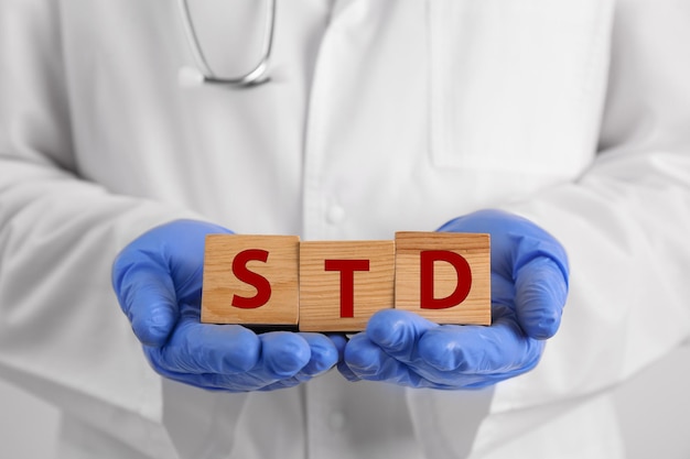Доктор держит деревянные кубики с аббревиатурой STD крупным планом