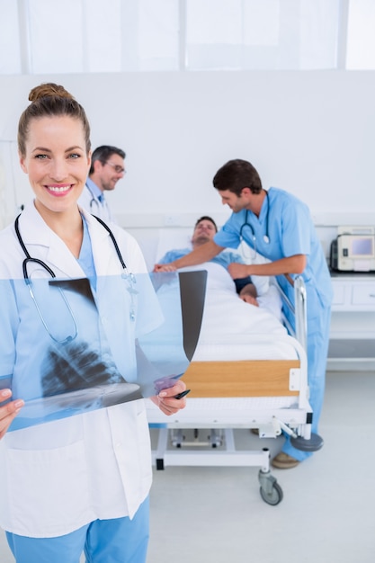 Doctor holding x-ray with surgeons and patient in hospital