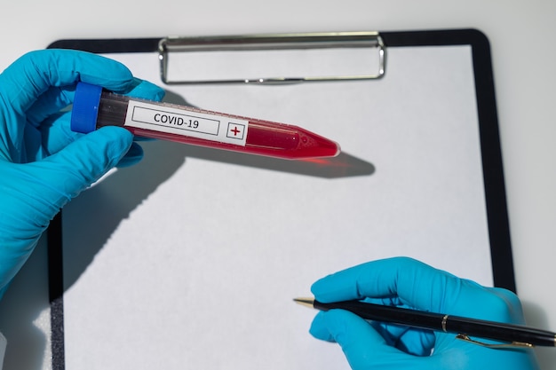 Photo the doctor holds an ampoule with the coronavirus vaccine in his hands vaccine against covid in hands...