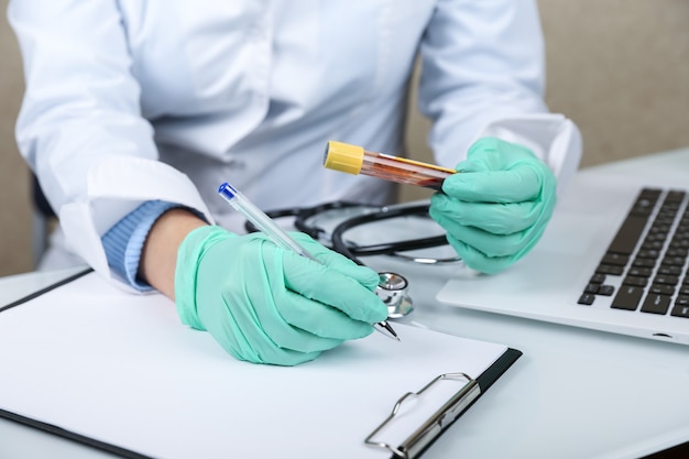 doctor holds blood test tube and fills a blank