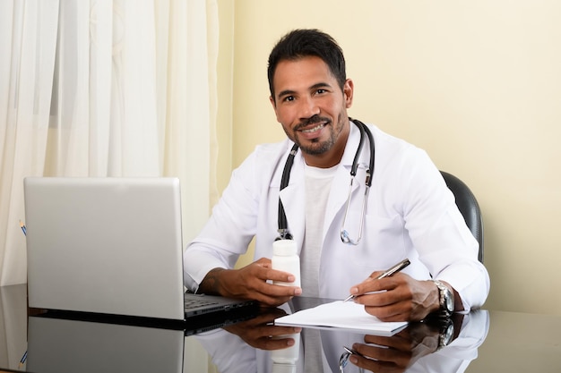 doctor holds a bottle of medicine and makes notes, looks at camera