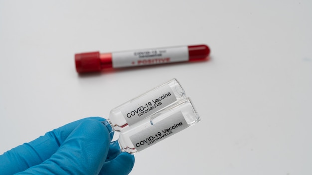 Doctor holds COVID 19 Coronavirus vaccine in his hand, infected blood sample in the sample tube, Vaccine and syringe injection It use for prevention, immunization and treatment from COVID-19