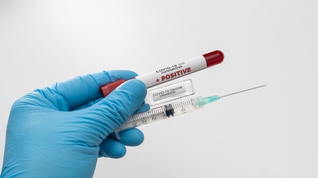 Doctor holds COVID 19 Coronavirus vaccine in his hand, infected blood sample in the sample tube, Vaccine and syringe injection It use for prevention, immunization and treatment from COVID-19