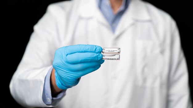 Doctor holds COVID 19 Coronavirus vaccine in his hand, infected blood sample in the sample tube, Vaccine and syringe injection It use for prevention, immunization and treatment from COVID-19