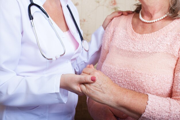 doctor holds an elderly woman by the hand comforting