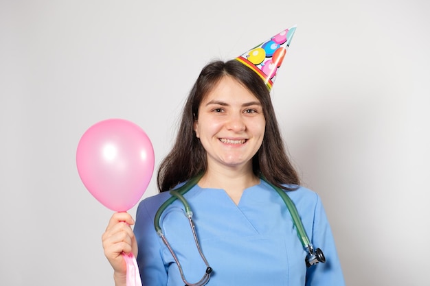 The doctor holds a festive balloon and smiles happy doctor's day