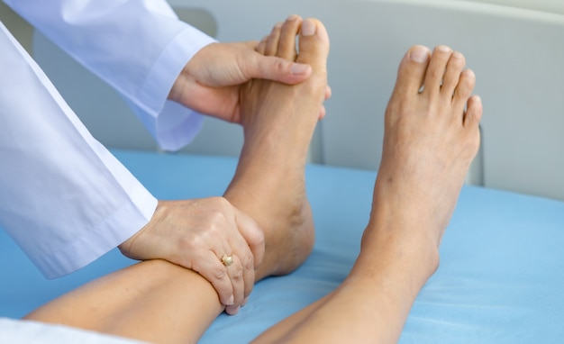 Photo doctor holds legs patient on bed in hospital and checkup nervous system for cure and treatment. concept of guillain barre syndrome and numb hands disease or vaccine side effect.