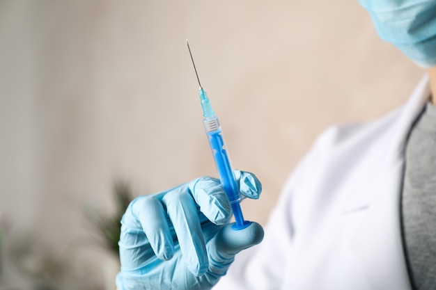 Doctor holds medical syringe of vaccine, injection on brown background.  Healthcare and medical concept